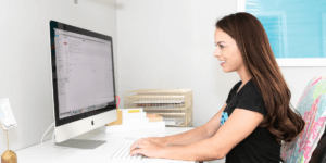 Nicole Aucoin sitting at a computer writing an ad to hire a nutrition coach