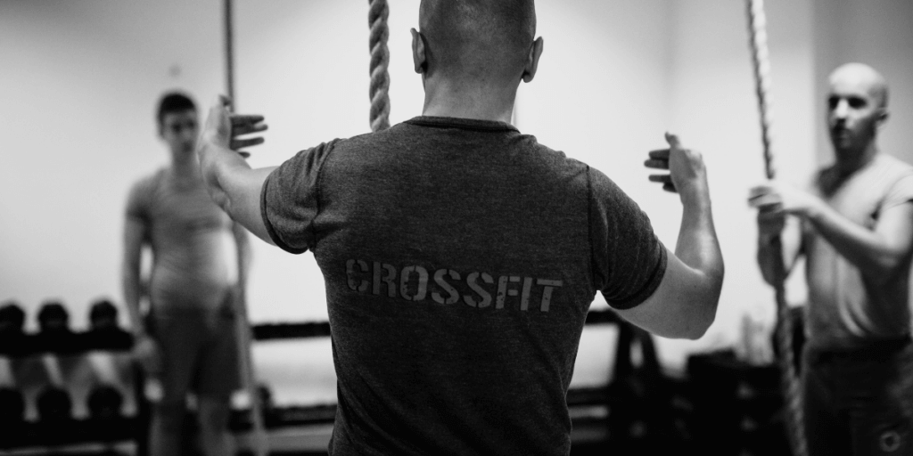 person coaching a crossfit class with the word crossfit on the back of shirt